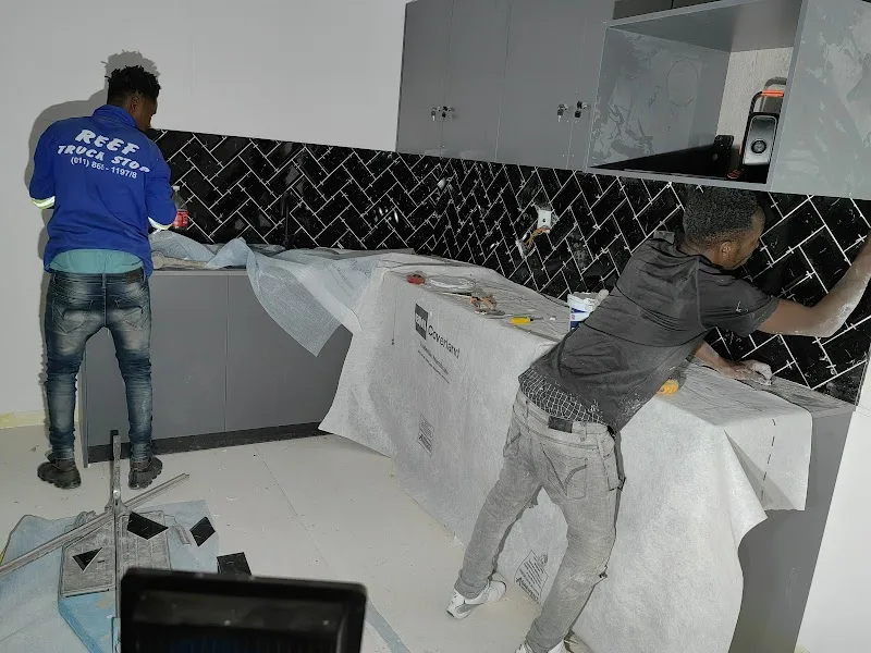 Tilers installing a black herringbone kitchen splashback